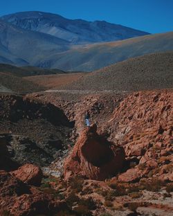 Man standing on rock against sky