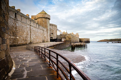 Stone slab bridge on the seashore near the medieval walls of the city against the sky