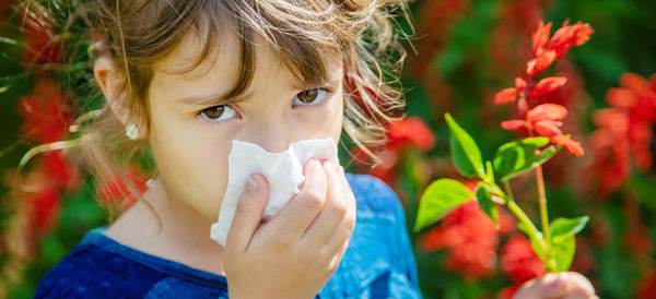 Portrait of sick girl having allergy wiping nose