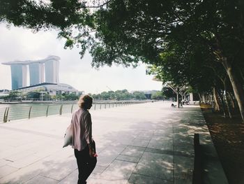 Rear view of woman walking on footpath in city