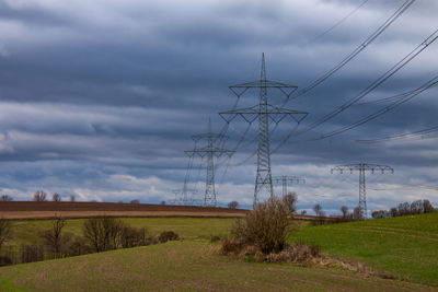 Electricity pylon on field against sky