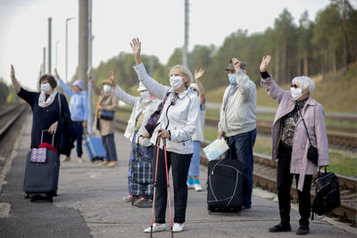 Group of elderly seniors people with face masks waiting train before traveling during a pandemic