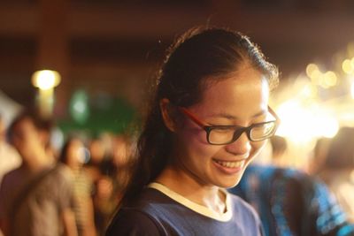 Close-up of smiling young woman in illuminated city