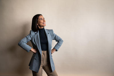 Portrait of young woman standing against wall