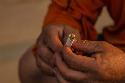 Cropped image of hands holding cigarette
