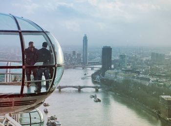 Friends in london eye over thames river against sky