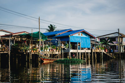 Houses by river against sky