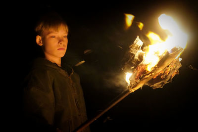 Portrait of teenage boy holding fire at night