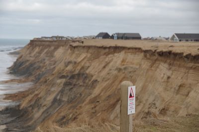 Information sign on beach against sky