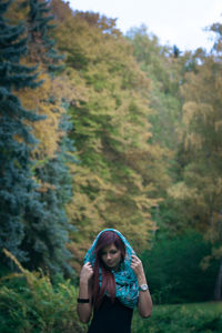 Woman wearing headscarf standing on field against trees