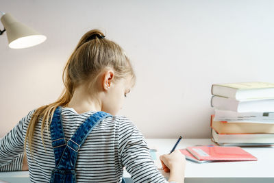 Rear view of girl studying at home