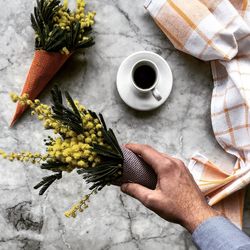 Cropped image of man holding yellow flower bouquet at marble table