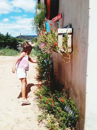 Side view of girl with flowers against plants