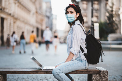 Portrait of young woman using laptop at street