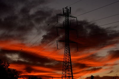 Low angle view of silhouette electricity pylon against dramatic sky