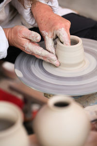 Midsection of man making clay pot