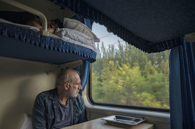 Rear view of man looking through window