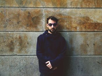 Portrait of mid adult man wearing sunglasses while standing against wall