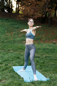 The relaxed girl is doing yoga in the park on carpet