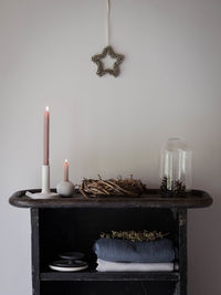 Close-up of candles on table against wall at home