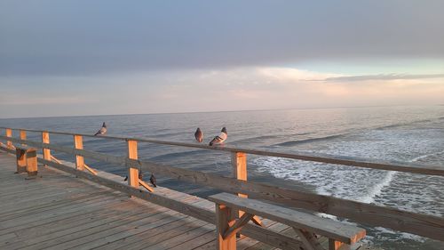 Pier over sea against sky during sunset