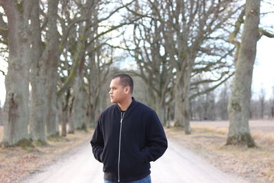 Young man looking away while standing on road