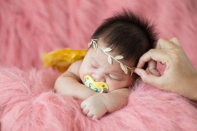 A cute newborn boy wearing a headband and small angle wing sleeping on a pink soft blanket, infant,