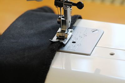 Close-up of machine sewing fabric on table
