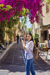 Portrait of woman photographing in city