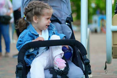Girl crying while sitting in baby stroller