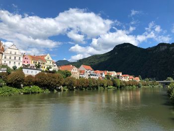 Buildings by river against sky