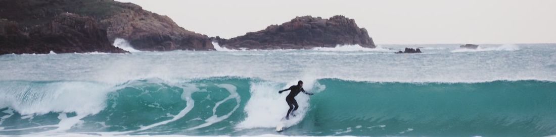 Man surfing in sea against sky