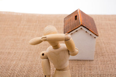 High angle view of wooden figurine and model home on burlap