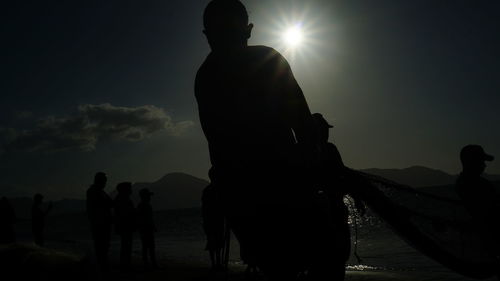 Silhouette people at beach against sky during sunset