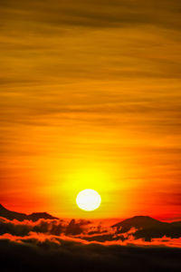 Silhouette landscape against orange sky