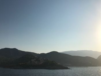 Scenic view of sea and mountains against clear sky