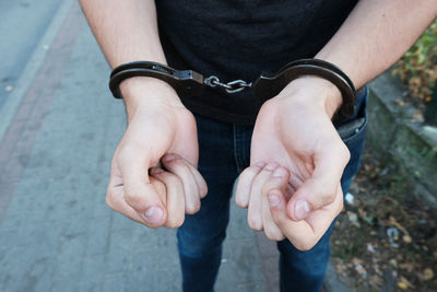 Midsection of man with handcuffs standing on footpath