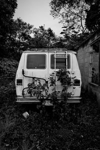 Abandoned motorcycle on field against trees