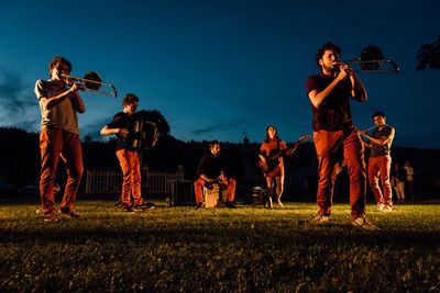 People playing on field against sky at night
