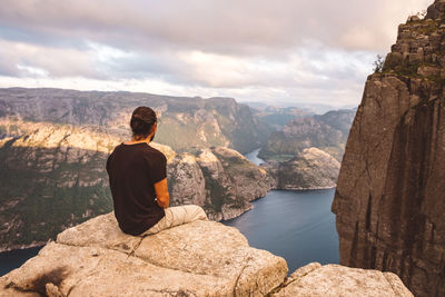 Man sitting in rock at edge of cliff at preikestolen, norway