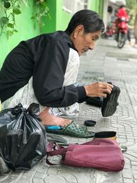 Man looking away while sitting on footpath