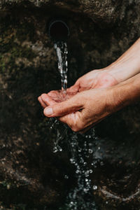 Hand holding water flowing from faucet