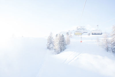 Snow covered overhead cable car against sky during winter