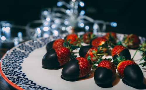 Strawberries on the plate covered with chocolate and decorated with lights. 