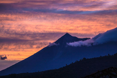 Scenic view of volcanic mountain against sky during sunset