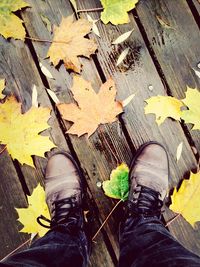 Low section of man standing in autumn leaves