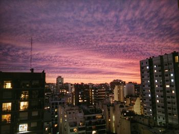 View of illuminated cityscape against cloudy sky