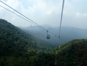 Overhead cable car over mountains against sky