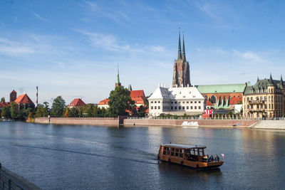 Boat in river by buildings against sky in city