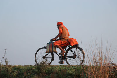 Man riding bicycle on field against clear sky